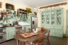 a kitchen with green cabinets and an old fashioned dining room table in front of the stove