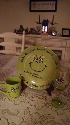 two cups and a plate with faces on them sitting on a table in front of a dresser