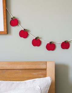 red crocheted apples hanging from a string on a bed