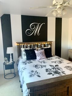 a bedroom with black and white striped walls has a large monogrammed sign above the bed