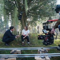 three people sitting on the ground in front of a camera set up for a film