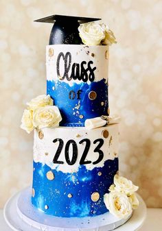 a blue and white graduation cake with flowers on top