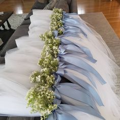 a blue and white wedding dress laying on top of a couch with flowers in it