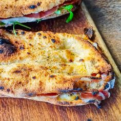 two toasted sandwiches sitting on top of a wooden cutting board next to each other