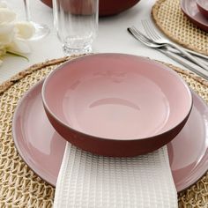 a table set with pink plates and silverware