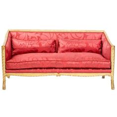 a red couch sitting on top of a white floor next to a wooden frame with gold trim