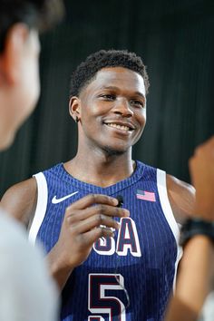 a young man is smiling and holding something in his hand while talking to someone else