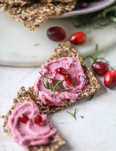 two pieces of bread with cranberry spread on them and cherries scattered around