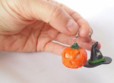 a hand holding a keychain with a pumpkin and witch hat attached to it