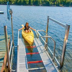 a woman sitting in a yellow kayak on a dock