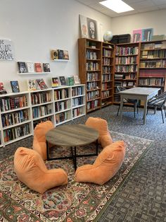 two orange chairs sitting in front of a coffee table on top of a rug next to bookshelves