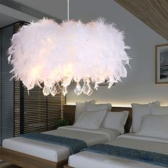 two beds in a room with white sheets and feathers hanging from the chandelier