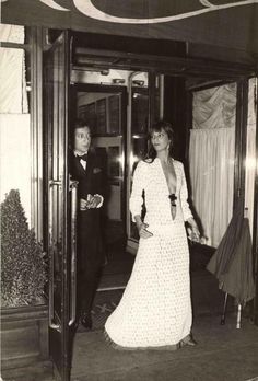 an old black and white photo of two people standing in front of a train door