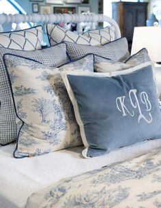 a bed topped with lots of blue and white pillows