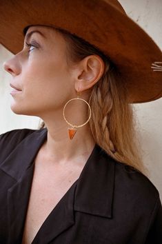 "Amplify your energy with our gorgeous gold hammered hoop earrings adorned with vibrant Carnelian pendants. The eye-catching Carnelian gemstone triangles add a pop of warm color, just like an orange sun at sunset.  Carnelian, known as the stone of motivation, brings a wave of positive energy to your aura. Feel the boost of vitality like a spark to a flame as you wear these earrings, empowering you to embrace each day with passion and fire. ▲ Carnelian gemstone triangle pendants ▲ 2\" gold hammered hoops ▲ Weight: .12 oz  ▲ Drop length: 3 1/4\" ▲ Handmade in Arizona Love hoop earrings as much as we do?  Shop them all here!  https://etsy.me/3txKbEn ✦ O R D E R - P R O C E S S I N G - T I M E S ✦ Jewelry & accessories ship out in 1-3 business days and orders with gemstone hangings ship out in Carnelian Jewelry, Hammered Hoop Earrings, Carnelian Pendant, Triangle Pendant, Hammered Gold, Jewelry Earrings Hoops, Gold Hoop, Minimalist Earrings, Gold Hoop Earrings