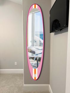 there is a pink and orange mirror on the wall in this room with grey walls