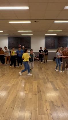 a group of people standing on top of a hard wood floor in an empty room