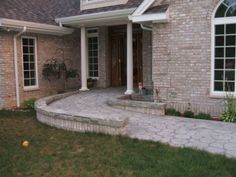 a brick house with steps leading up to the front door and side yard area,