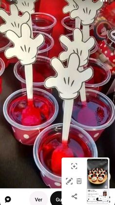 some cups filled with red liquid sitting on top of a black table covered in stickers