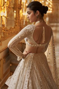 This lehenga set features delicate embroidery in ivory and gold sequin in a geometric pattern,. The full sleeves blouse has a plunging neckline and shows pearl and crystal tassels at the waist and wrist. It is paired with a matching four sided embroidered dupatta.From Seema Gujral's Inara collection. DELIVERY TIMEPlease allow 8-12 weeks for your outfit to arrive. FABRIC DETAILSNet Professional cleaning only. Sequin Lehenga, Seema Gujral, Gold Lehenga, Full Sleeve Blouse, Pearl Embroidery, Embroidered Belt, Indian Dresses Traditional, White Gown, Indian Bridal Dress