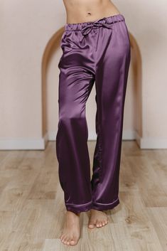 a woman in red pants standing on a wooden floor with her hands behind her back