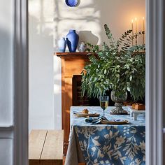 a dining room table with blue vases on top of it and candles in the background