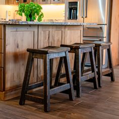 two stools are in the middle of a kitchen with an island and stainless steel appliances