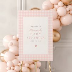 a baby shower sign surrounded by balloons in front of a door with a pink and white checkered welcome sign