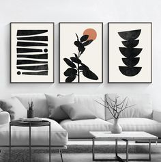 three black and white paintings hanging on the wall above a couch in a living room