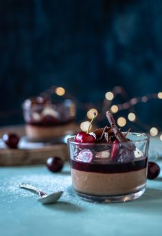 two small desserts with cherries and chocolate on the top are sitting on a table