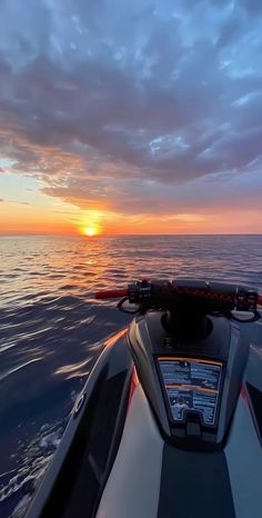 the sun is setting over the ocean as seen from a speed boat in the water