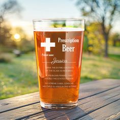 a glass of beer sitting on top of a wooden table in front of a field