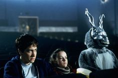 two people sitting next to each other in front of a rabbit costume on the screen