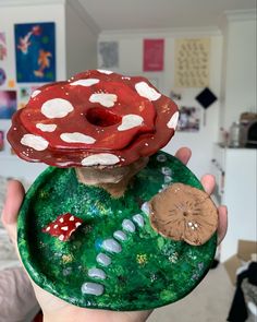 a person holding up a clay plate with a mushroom on top of it in their hand