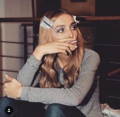 a woman sitting on the floor with her hand over her mouth and looking at the camera