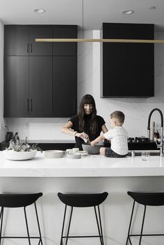 a mother and her son are preparing food in the kitchen at the island countertop