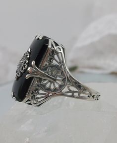 Black Glass/Stone & CZ Ring Grace Design#233 Custom Made I now offer this lovely Antique Art Deco/Edwardian design ring in sterling silver. This gorgeous ring is set with a stunning floral filigree embellished black glass/resin with a centered set 1mm white CZ. The Black glass is 18mm Long by 19mm Wide. The ring sits 19mm NS in the finger and 10mm EW on the finger. The inside of the band is marked 925 for sterling. Notice the beautiful leaf geometric design of the filigree band and setting. Elegant Wedding Rings With Gemstone Accents, Formal Cubic Zirconia Jewelry With Filigree Details, Formal Cubic Zirconia Jewelry With Filigree, Elegant Jewelry Ring With Gemstone Accents, Elegant Sterling Silver Gemstones For Wedding, White Gold Jewelry With Center Stone For Evening, Silver Filigree Ring With Stone Setting For Formal Occasions, Silver Filigree Ring For Formal Occasion, Antique Jewelry With Gemstone Accents For Wedding