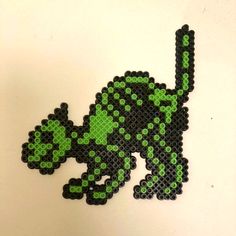 a green and black pixel art piece sitting on top of a white table