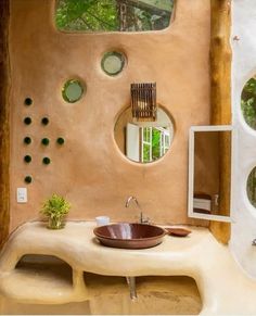 the bathroom is decorated in earth tones and features round mirrors on the wall, an oval sink with a wooden bowl