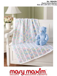 a blue teddy bear sitting on top of a white bench next to a blanket and lamp