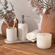 a candle, soap dispenser and some flowers on a wooden counter top