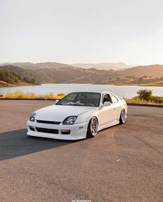 a white car parked on the side of a road next to a body of water