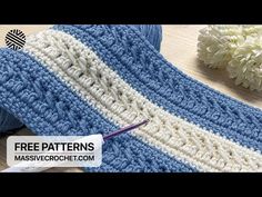 a crocheted blue and white blanket next to a flower