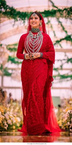 a woman in a red dress is walking down the runway with her hands on her hips