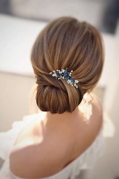 a woman with her hair in a low bun wearing a blue and white flower clip