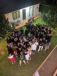 a group of people standing in front of a house at night with their hands up