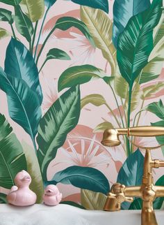 a bathroom with tropical wallpaper and gold faucet in the bathtub next to it