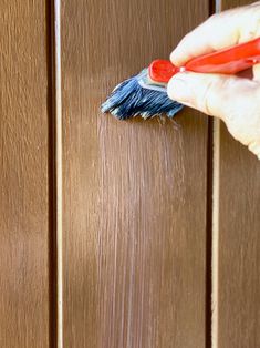 a person using a brush to paint the side of a wooden door with wood stain