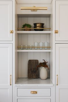 a kitchen with white cabinets and gold handles