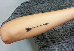 a woman's arm with an arrow tattoo on the left side of her arm